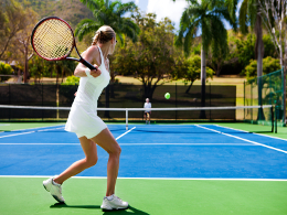 two people playing tennis in a tropical setting